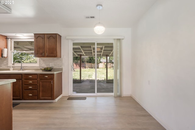 6139 SE 103rd Ave, Portland, OR 97266 - kitchen with light wood-type flooring, light countertops, decorative backsplash, and pendant lighting