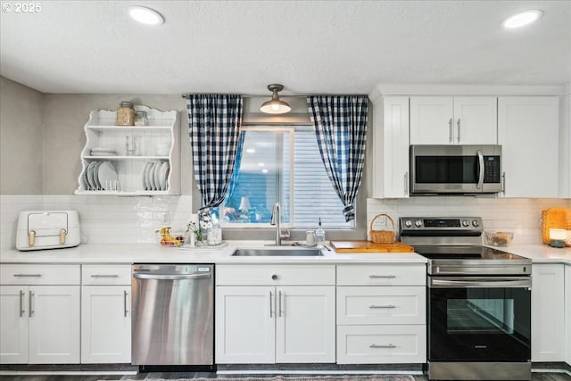 kitchen with appliances with stainless steel finishes, a sink, open shelves, light countertops, and a textured ceiling