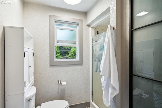 bathroom featuring toilet, a shower with door, and a textured wall