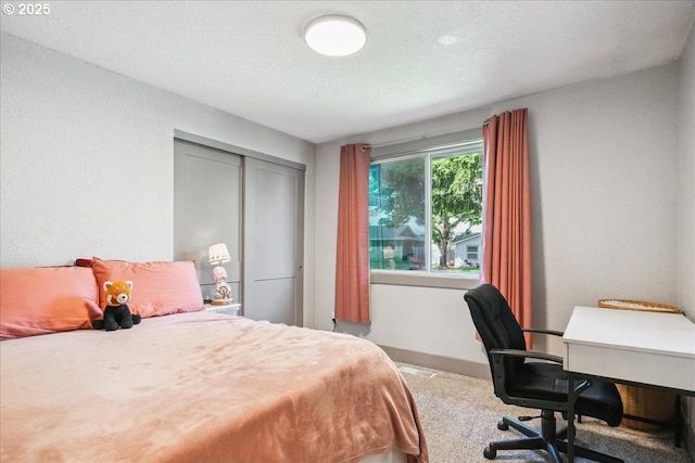 bedroom with carpet floors, a desk, a closet, baseboards, and a textured ceiling