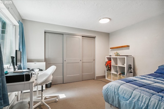 bedroom featuring carpet, a textured ceiling, a closet, and a desk