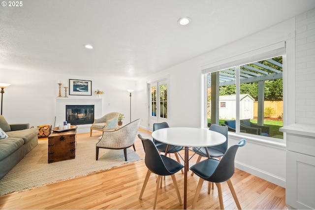 dining area featuring light wood-type flooring, a glass covered fireplace, baseboards, and recessed lighting