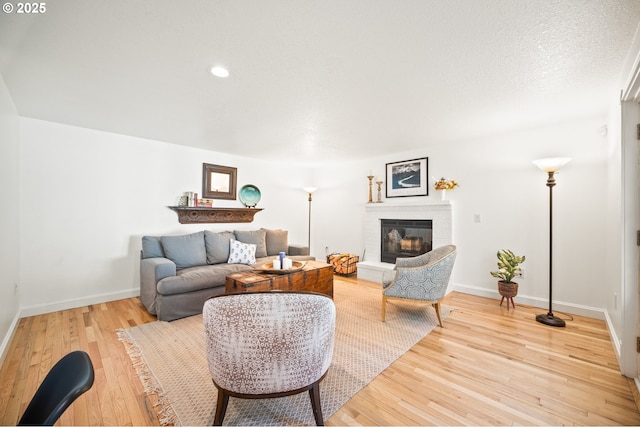 living area with recessed lighting, a fireplace, light wood-style flooring, and baseboards