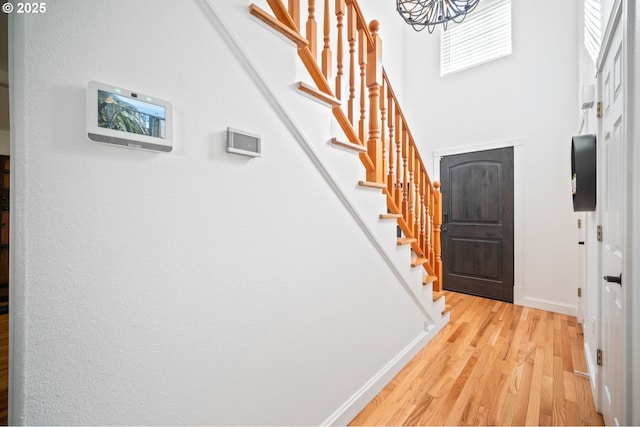 entrance foyer featuring light wood-type flooring, a high ceiling, stairway, and baseboards