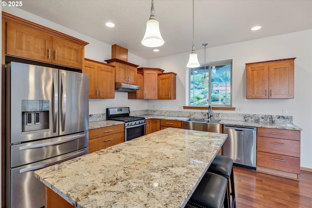 kitchen featuring decorative light fixtures, stainless steel appliances, a kitchen bar, a kitchen island, and sink