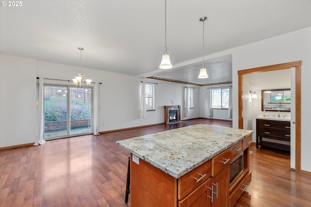 kitchen with decorative light fixtures, an inviting chandelier, light stone counters, and a kitchen island