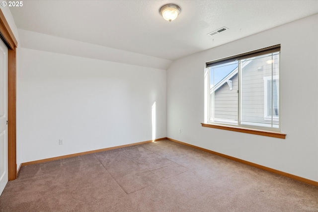 carpeted spare room featuring vaulted ceiling