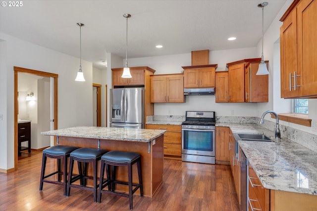 kitchen featuring hanging light fixtures, a kitchen island, appliances with stainless steel finishes, a kitchen breakfast bar, and sink