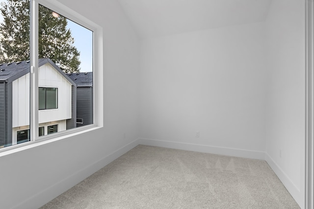 spare room with carpet floors, baseboards, and lofted ceiling