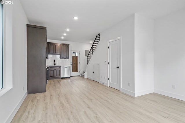 unfurnished living room featuring light wood-style flooring, recessed lighting, a sink, baseboards, and stairway