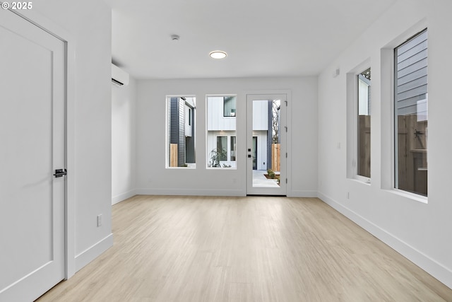 spare room featuring baseboards, wood finished floors, and a wall mounted AC