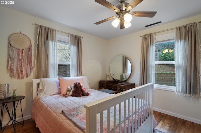 bedroom with visible vents, baseboards, ceiling fan, and dark wood-type flooring