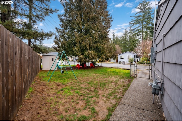 view of yard featuring a gate, a playground, fence, and an outdoor structure