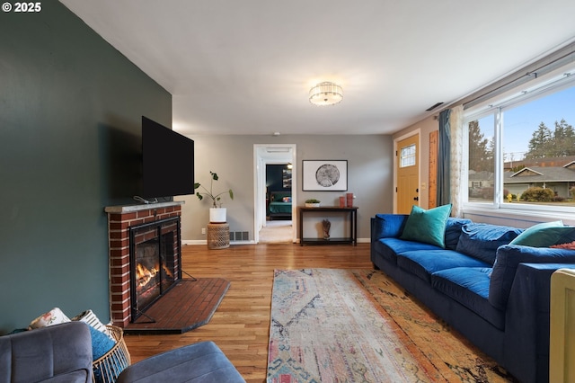 living area with baseboards, visible vents, a fireplace, and light wood finished floors