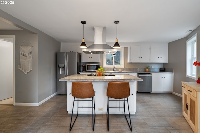 kitchen featuring pendant lighting, appliances with stainless steel finishes, white cabinetry, a kitchen island, and island range hood