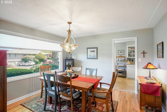dining space with light wood-style flooring and baseboards