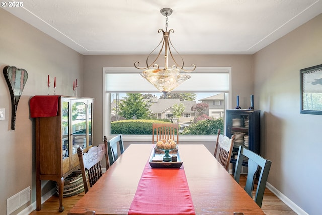dining room featuring a chandelier, plenty of natural light, wood finished floors, and baseboards