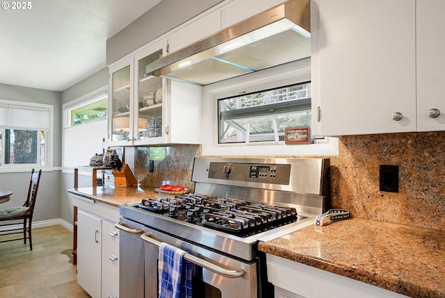 kitchen with stainless steel range with gas stovetop, baseboards, white cabinetry, and under cabinet range hood