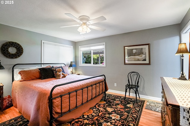 bedroom featuring wood finished floors, baseboards, and a ceiling fan