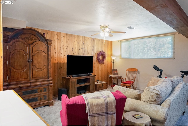 living area featuring ceiling fan, carpet floors, and wood walls
