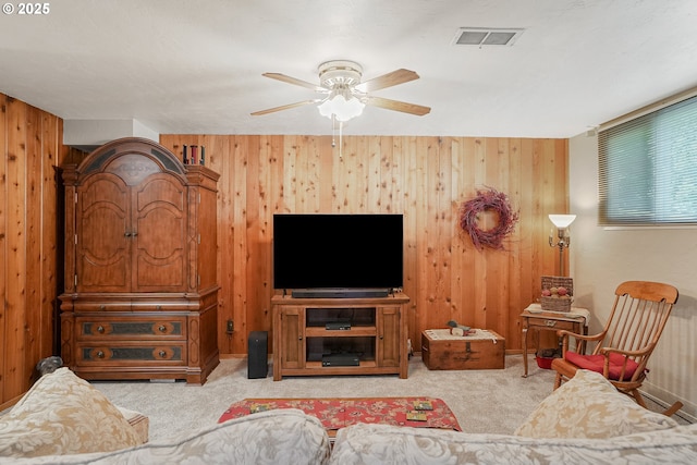 carpeted living area with wood walls and a ceiling fan