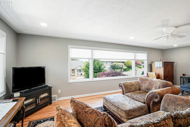 living room featuring light wood finished floors, a ceiling fan, baseboards, and recessed lighting