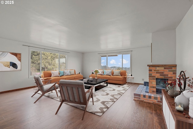 living room with a fireplace, baseboards, and wood finished floors