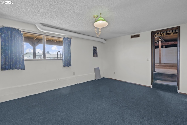 spare room featuring a textured ceiling and dark colored carpet