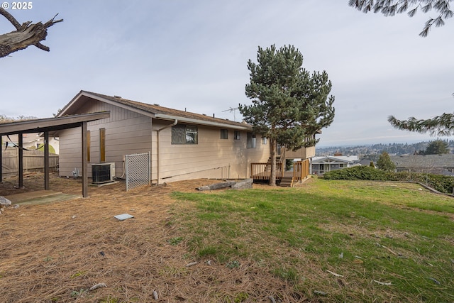 view of side of property with a wooden deck, a yard, and cooling unit