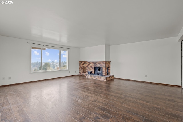 unfurnished living room featuring a brick fireplace and dark wood-type flooring