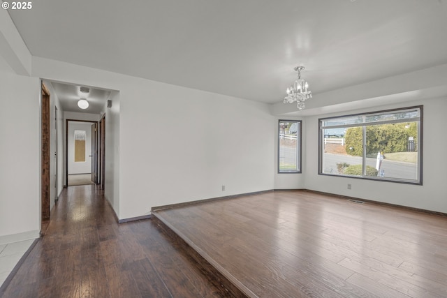 spare room with wood-type flooring and an inviting chandelier