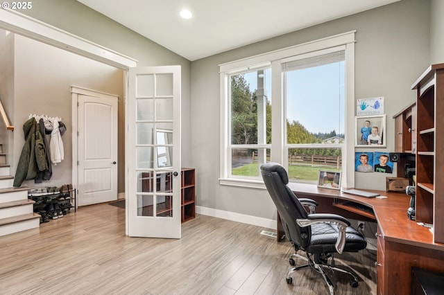 office area with light wood-style floors, a wealth of natural light, vaulted ceiling, and baseboards