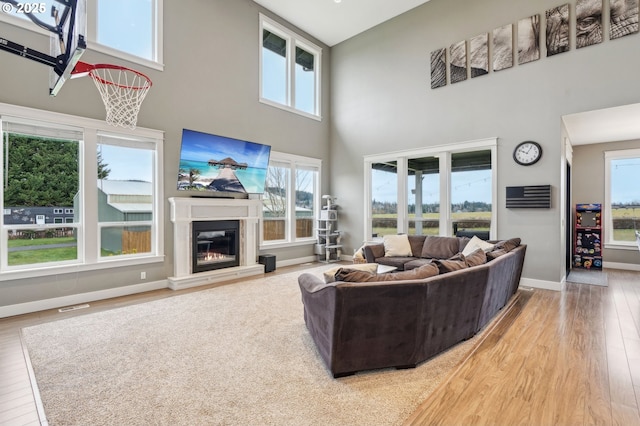 living room featuring light wood-type flooring, baseboards, visible vents, and a glass covered fireplace