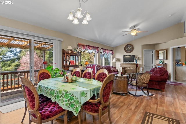 dining area with a fireplace, lofted ceiling, ceiling fan with notable chandelier, and light wood finished floors