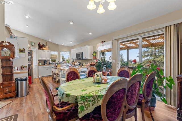 dining room with a wealth of natural light, a chandelier, light wood-type flooring, and vaulted ceiling