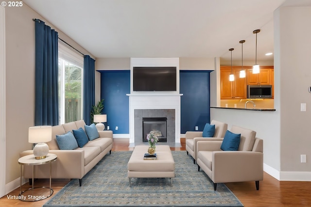 living area featuring dark wood-style flooring, a fireplace, and baseboards