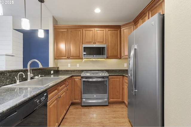 kitchen featuring brown cabinetry, pendant lighting, stainless steel appliances, and a sink