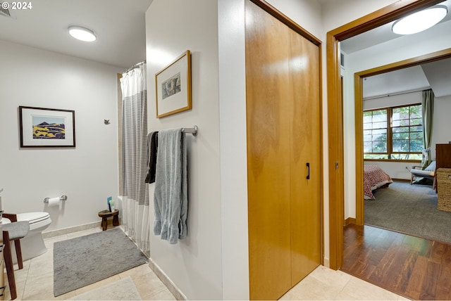 full bathroom featuring baseboards and toilet