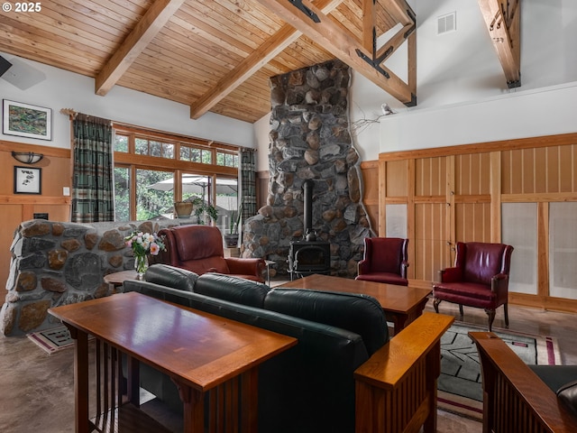 living area with concrete flooring, wainscoting, beam ceiling, and a wood stove