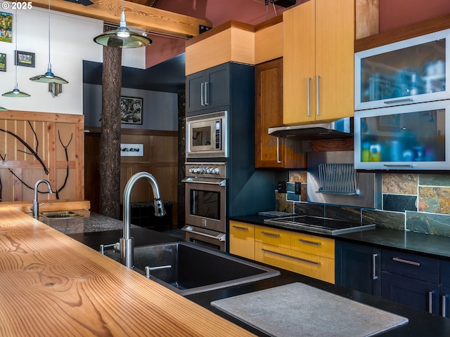 kitchen featuring a sink, under cabinet range hood, appliances with stainless steel finishes, and backsplash