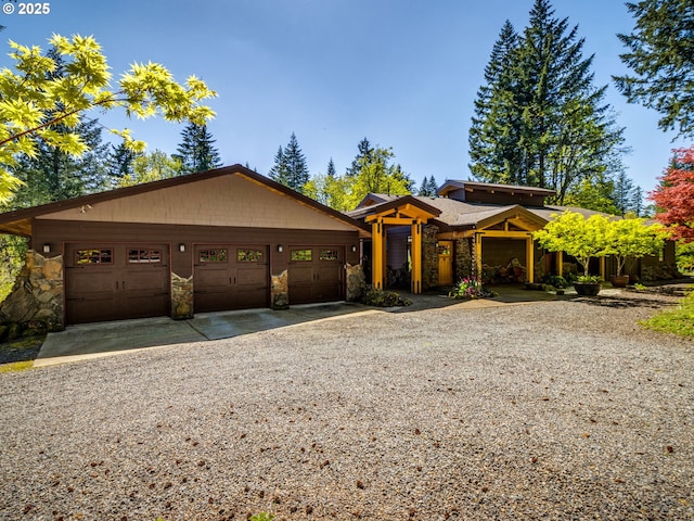 view of front of property with an attached garage, driveway, and stone siding