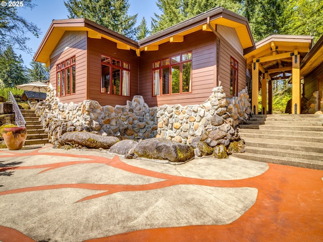 view of side of home with stairway and stone siding