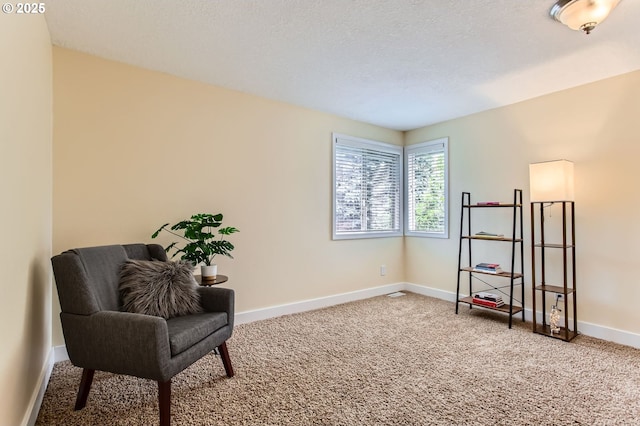 living area featuring carpet floors, baseboards, and a textured ceiling