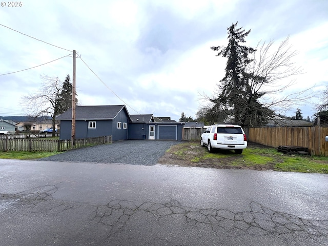 view of front of property featuring driveway, a garage, and fence