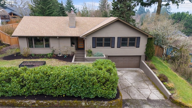 ranch-style home with fence, roof with shingles, concrete driveway, a garage, and a chimney