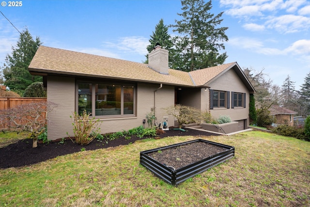 rear view of property with brick siding, fence, a chimney, a yard, and a vegetable garden