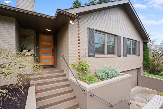 doorway to property featuring a garage and brick siding