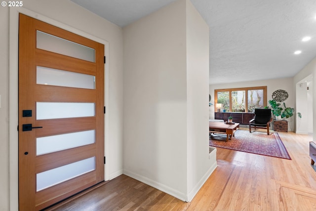 entrance foyer featuring recessed lighting, baseboards, a textured ceiling, and wood finished floors