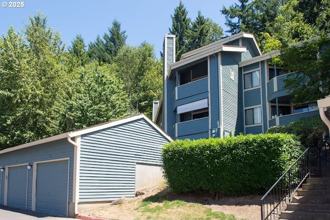 view of side of property with a detached garage, stairs, and a chimney