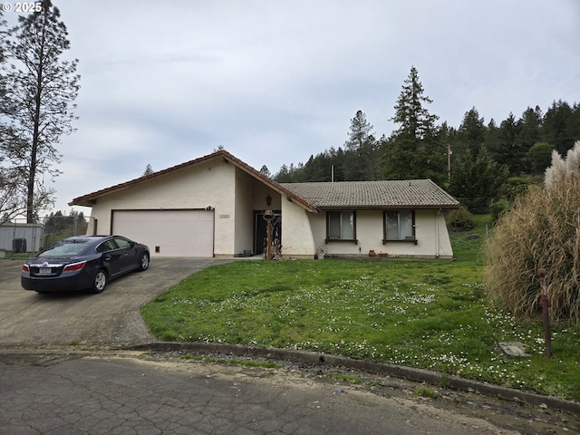 view of front of house featuring stucco siding, driveway, a tile roof, a front yard, and an attached garage